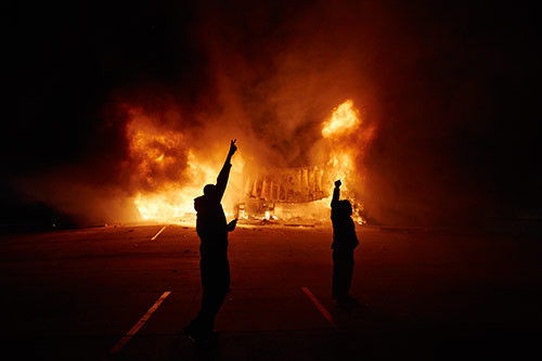Onlookers stand on West Florissant Avenue as an AutoZone burns early Tuesday, Nov. 25, 2014 in Dellwood, Mo. A grand jury decided not to charge Ferguson police officer Darren Wilson in the fatal shooting of Michael Brown.
