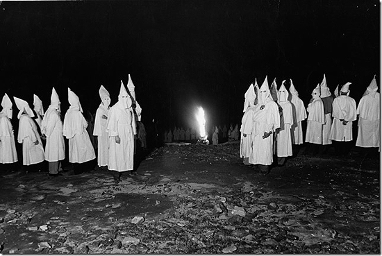 Ku Klux Klan members standing near a burning cross during an initiation ceremony, Atlanta, Georgai, 1948