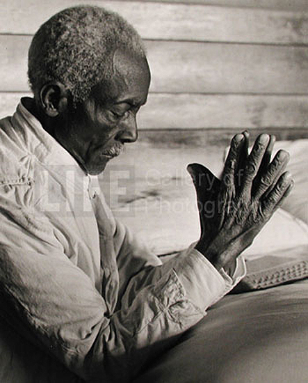African American sharecropper saying his evening prayers as he kneels at bedside at home., 1936