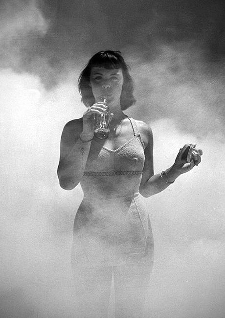 Kay Heffernon enjoys a hot dog and a Coke,  while DDT is sprayed to supposedly demonstrate it won't contaminate her, Jones beach, NY 1948<br/>