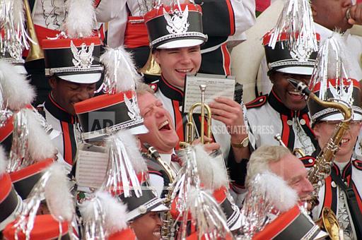 President-elect Bill Clinton leans back and laughs as he plays the saxophone with the Sugar Bear marching band of Central High School during a City Hall rally in Macon, Ga, November 23, 1992