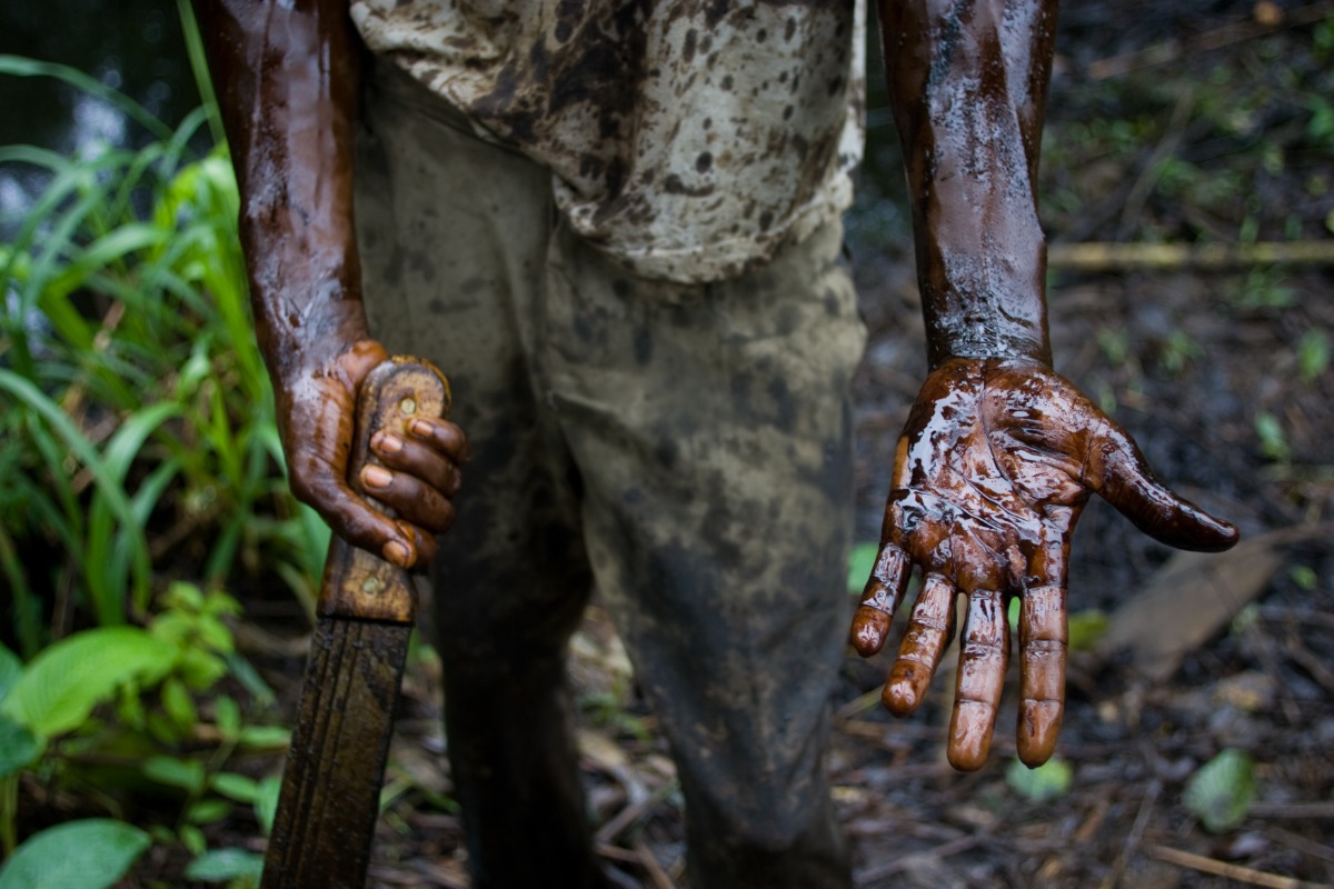 A worker subcontracted by Shell Oil Company cleans up an oil spill from a well owned by Shell that had been left abandoned for over 25 years, 2004