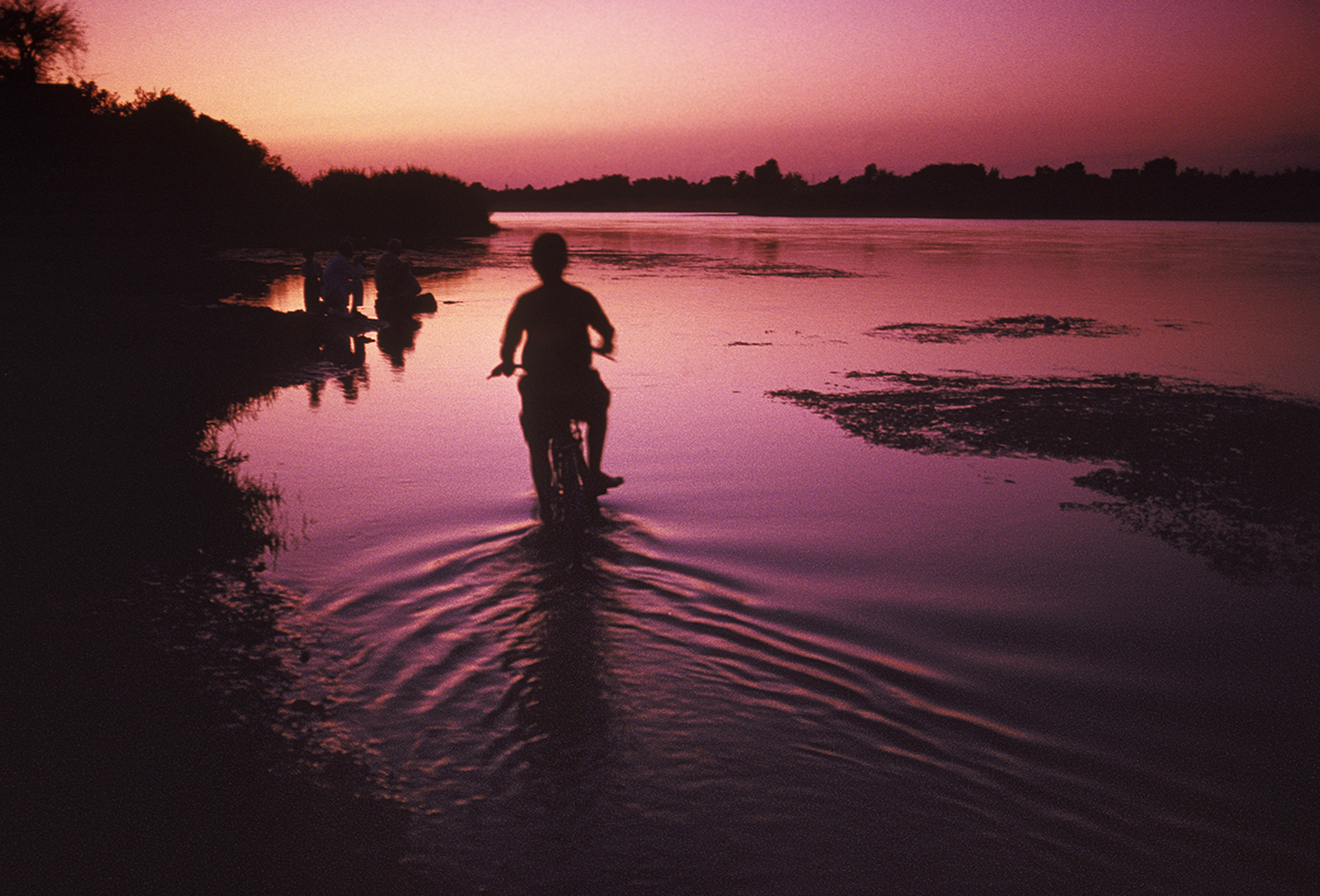 Boy riding his bike along the Euphrates River in the town of Dawr Al Zar. Syria, 1992