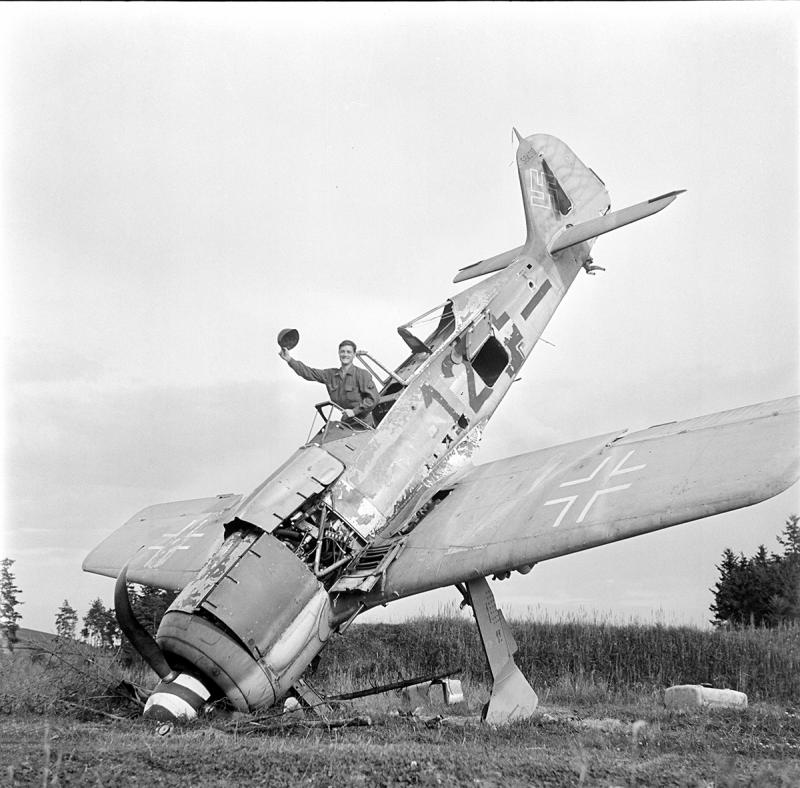 An American GI waving from a downed German Focke0Wulf fighter plane, Pocking, Bavaria, Germany, July, 1945 Archival Pigment Print