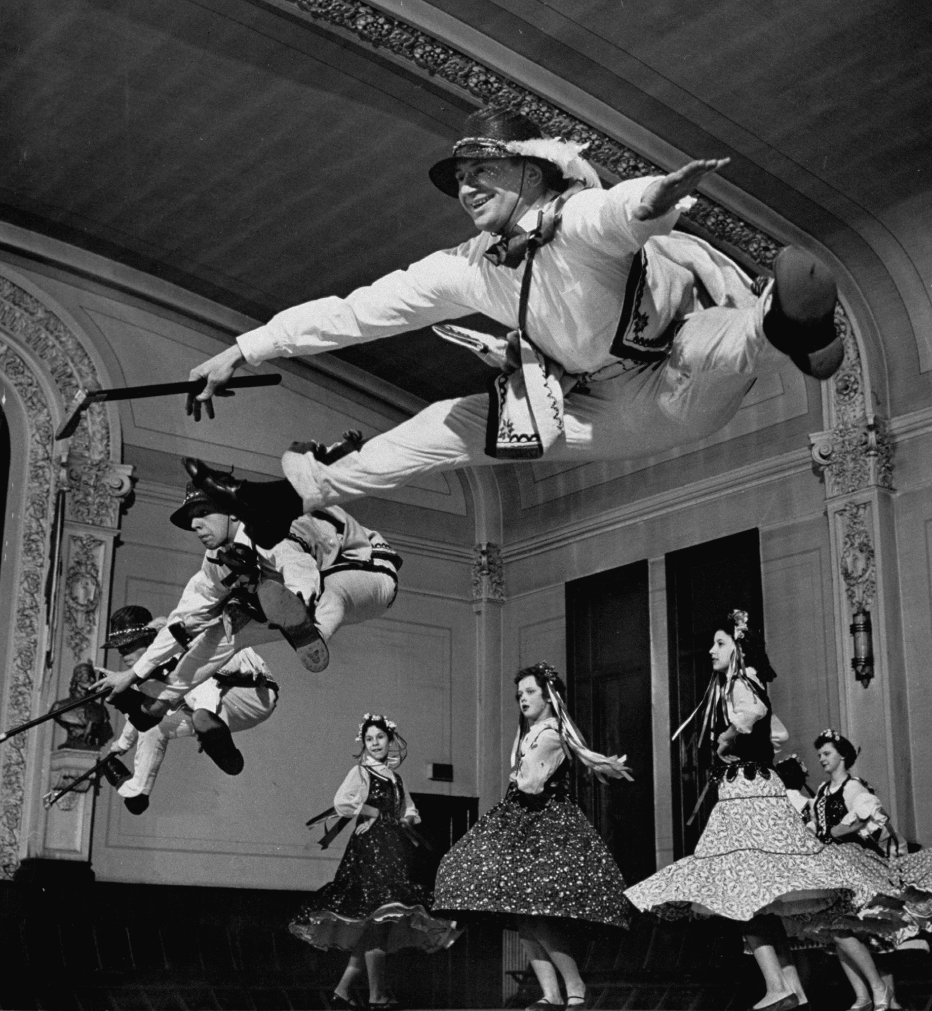Walter Karcz leaping in air as fellow members of amateur dance group practice an old Polish mountaineer dance called the Gorlaski at East Side Polish Hall, Detroit, MI, 1955
