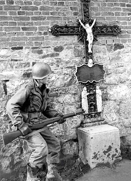 A US Soldier of the 83rd Infantry Division near a roadside crucifix in Belgium, Devember 25, 1944