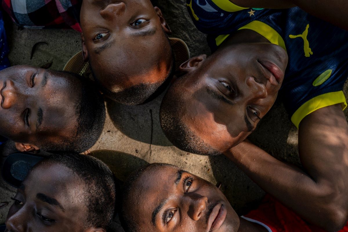 MObama Mchembe lying in the shade of cassia trees with his schoolmates Roger Muhud, 15; Islam Omari Mbena, 15; Omari Rashidi Mcharaga, 17; and Johnson Pascal, 15. Mwandege, Tanzania, 2024.