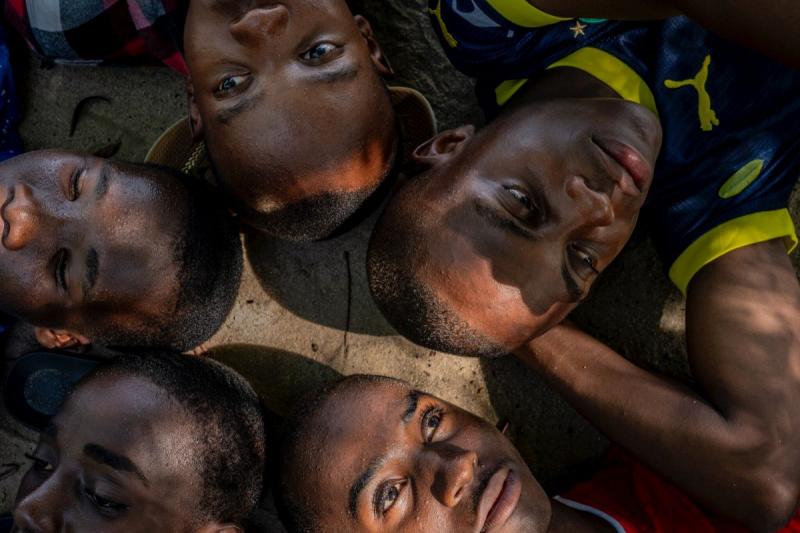 Photo: MObama Mchembe lying in the shade of cassia trees with his schoolmates Roger Muhud, 15; Islam Omari Mbena, 15; Omari Rashidi Mcharaga, 17; and Johnson Pascal, 15. Mwandege, Tanzania, 2024. Archival Pigment Print #2909