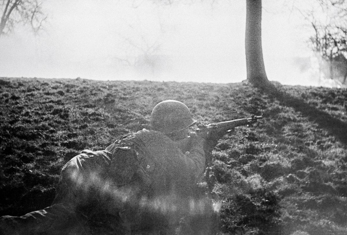 Soldier aiming his M1 at a German sniper, 1945