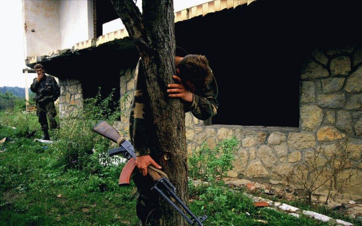 Senad Medanovic, sole survivor of a massacre at his home after a battle. He is standing on  what is believed to be a mass grave of 69 people, including members of his own family. Bosnia  1995