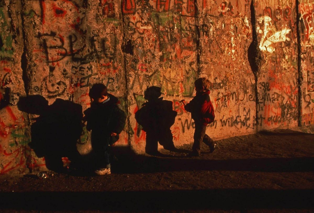 German children run alongside the Berlin wall as the wall came down and reunified East and West Germany. 1989