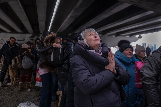 A woman prays as she escapes to safety from advancing Russian forces in her city, Irpin,  Ukraine 2022