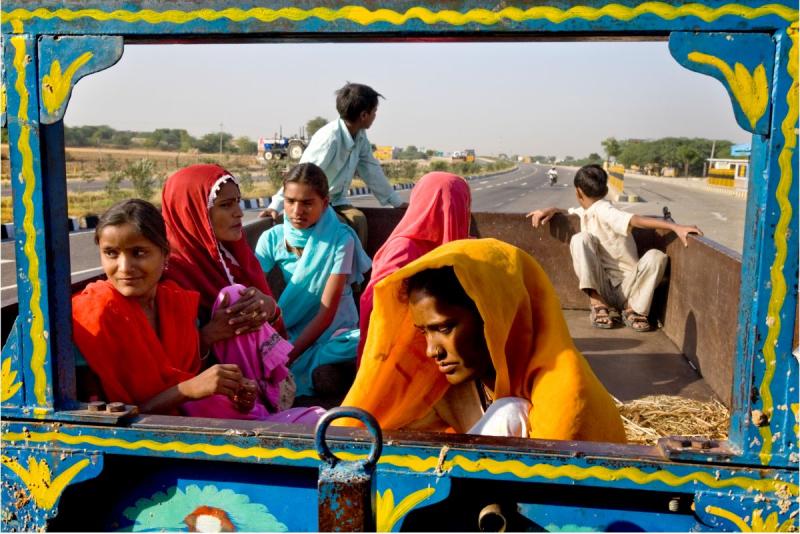 Photo: Day laborers hitch a ride a local tractor to get to work from their small villages just off the highway. Due to a shortage of water for the past few years in this area of Rajasthan, many of these people cannot farm their own lands. India Archival Pigment Print #3039