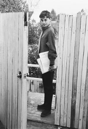 Audrey Hepburn waits by the gate of her apartment for the studio car. She was on the set of Sabrina by 6:30 every morning.