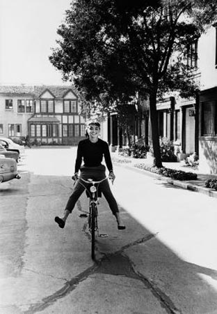 Audrey Hepburn rides a bike from the makeup department to the set of