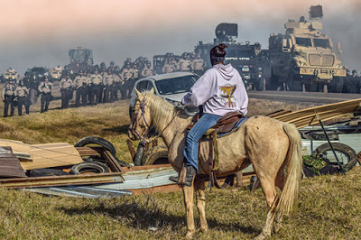 Native American woman on horse facing police line at Standing Rock