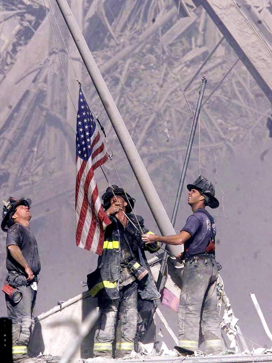 color photograph of 3 NY firemen raising an American Flag among the wreckafe of the World Trade Center on 9/11