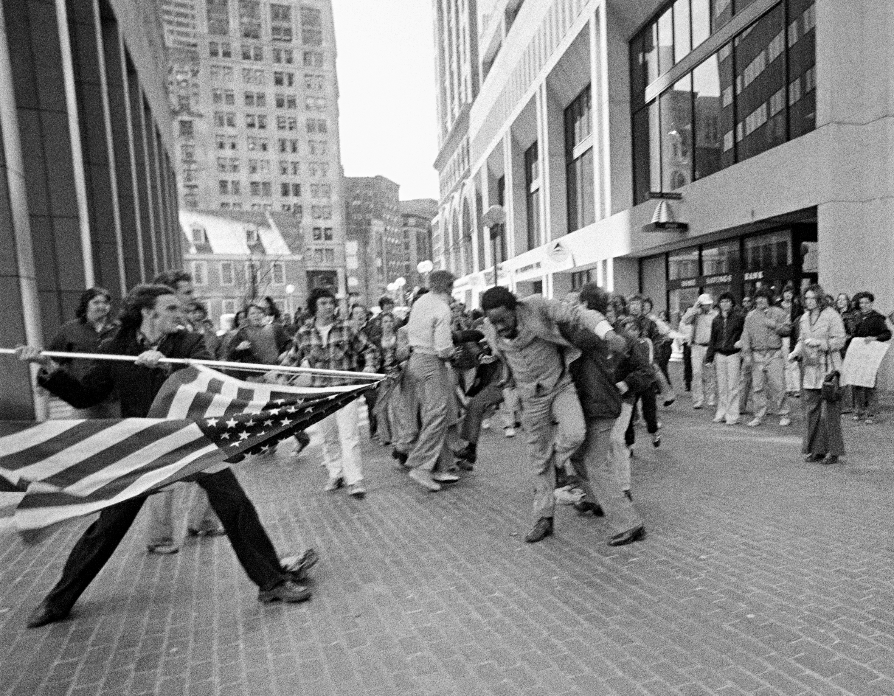 black and white a white protester outside Boston City Hall assaulting an African American attorney with the American flag in 1976