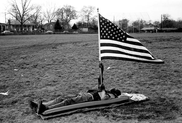 boy laying on ground holding an American Flag during the Selma March, 1965